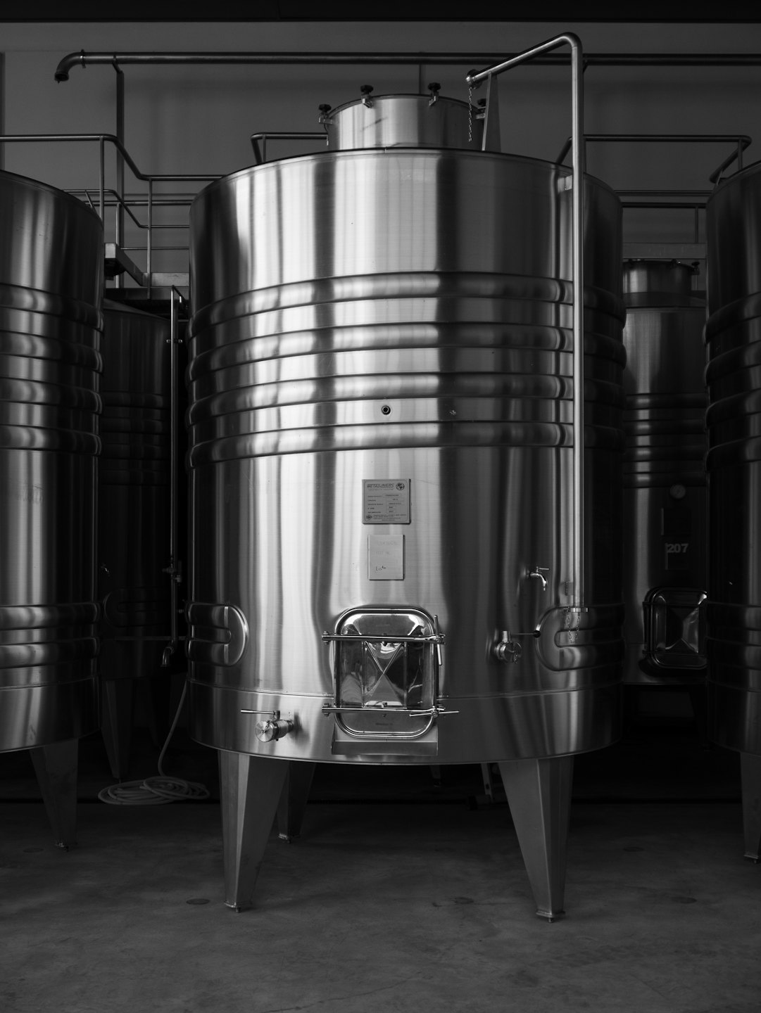 Large stainless steel fermentation tanks stand inside an industrial facility.